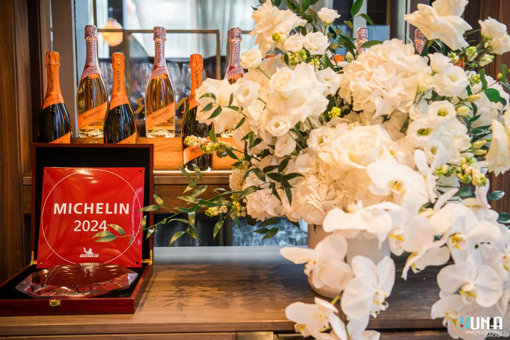 vancouver event photographer - Michelin 2024 award plaque displayed with white orchids and Mionetto Prosecco bottles at a Vancouver gala.