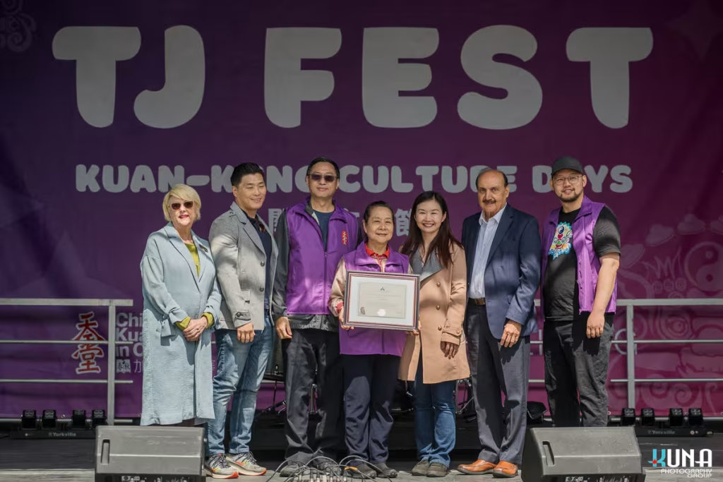 Dignitaries and organizers holding a framed certificate on stage to honor community contributions, documented by professional TJ Fest event photography.