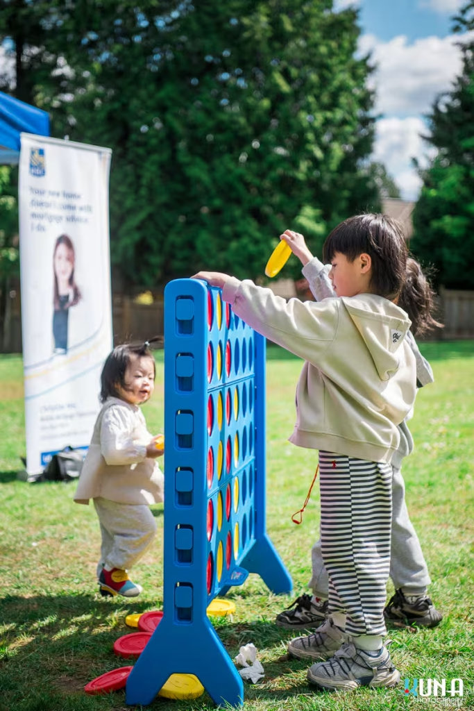 Kuna Photography: Vancouver Event Photographer. Toddlers playing with a giant Connect Four game at a family-friendly community festival in BC.