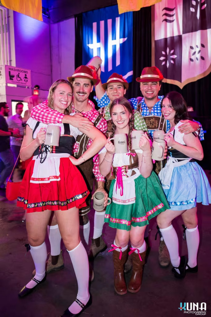 vancouver event photography - A group of six friends in matching traditional German festival attire posing with their Harvest Haus steins.