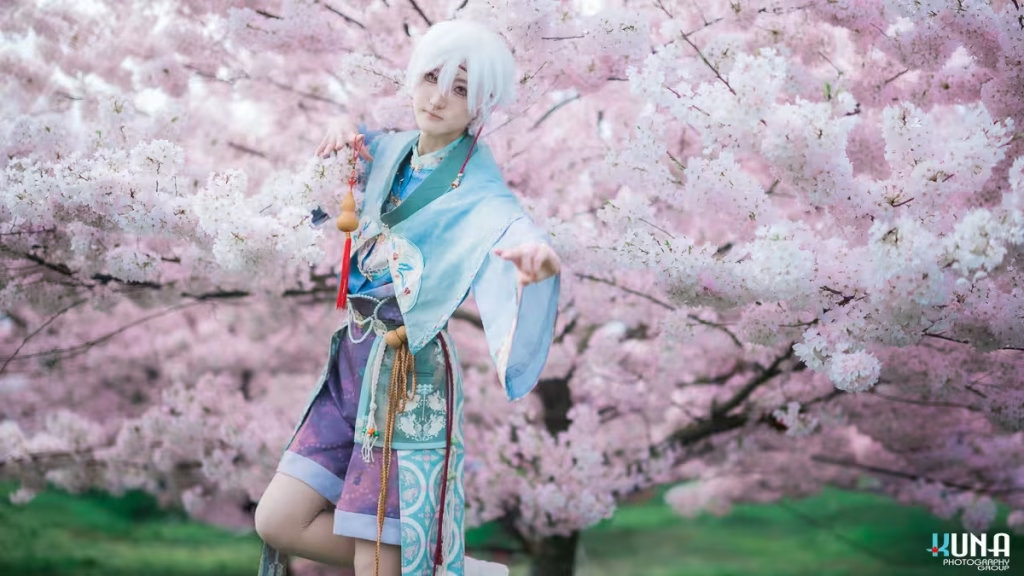 Full-body action pose of a white-haired fox boy cosplayer under a canopy of pink blossoms.