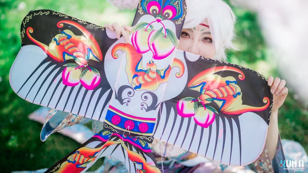 Close-up of a cosplayer peeking behind a traditional colorful swallow kite in a Vancouver garden.