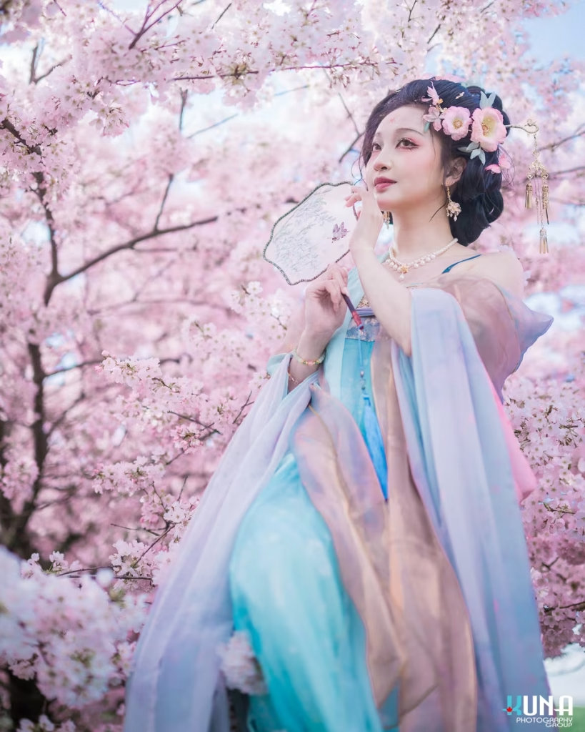 Standing Hanfu portrait looking afar with a floral fan in hand.