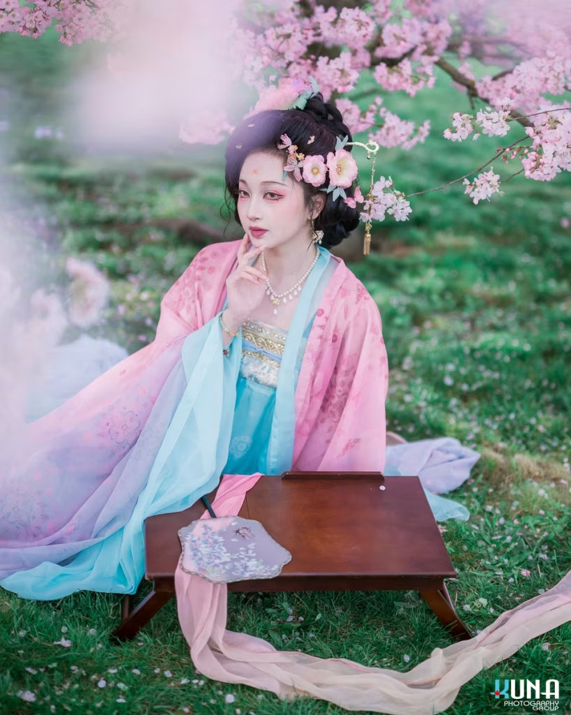 Lady in Hanfu resting at a traditional wooden desk outdoors.