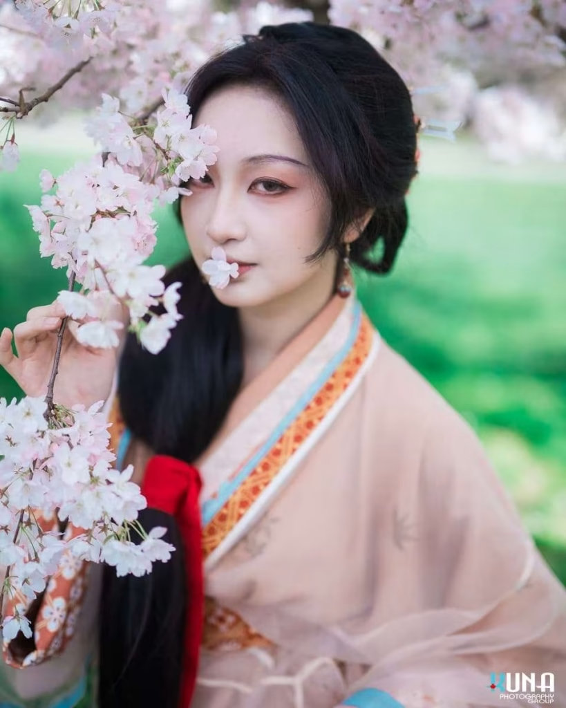 Hanfu portrait detail in Richmond: Close-up of subject's face with delicate makeup and cherry blossoms at Larry Berg Flight Path Park Vancouver.