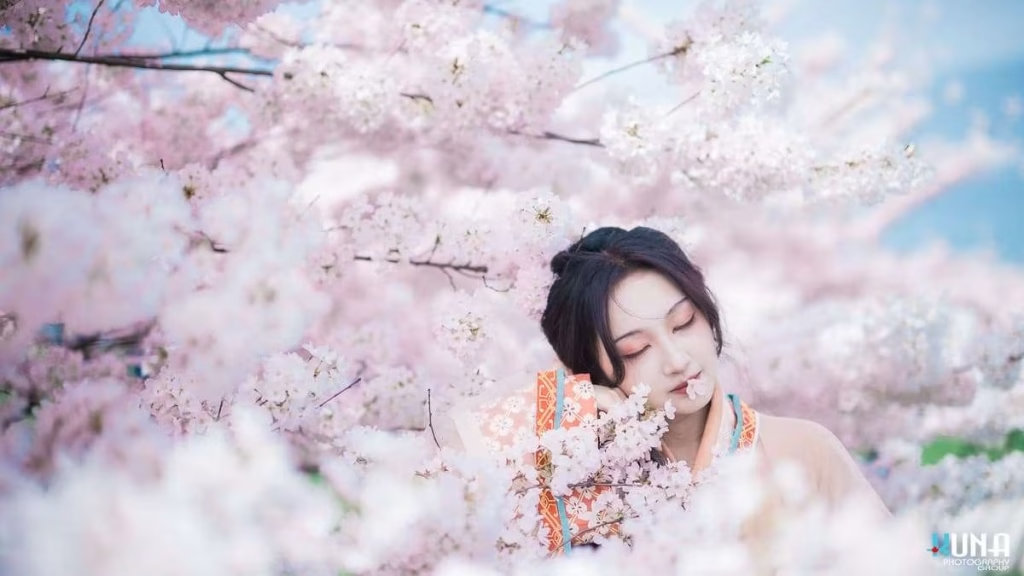 Intimate hanfu photography detail in Richmond: Model with eyes closed and petal on lips with contemplative expression at Larry Berg Flight Path Park Vancouver.