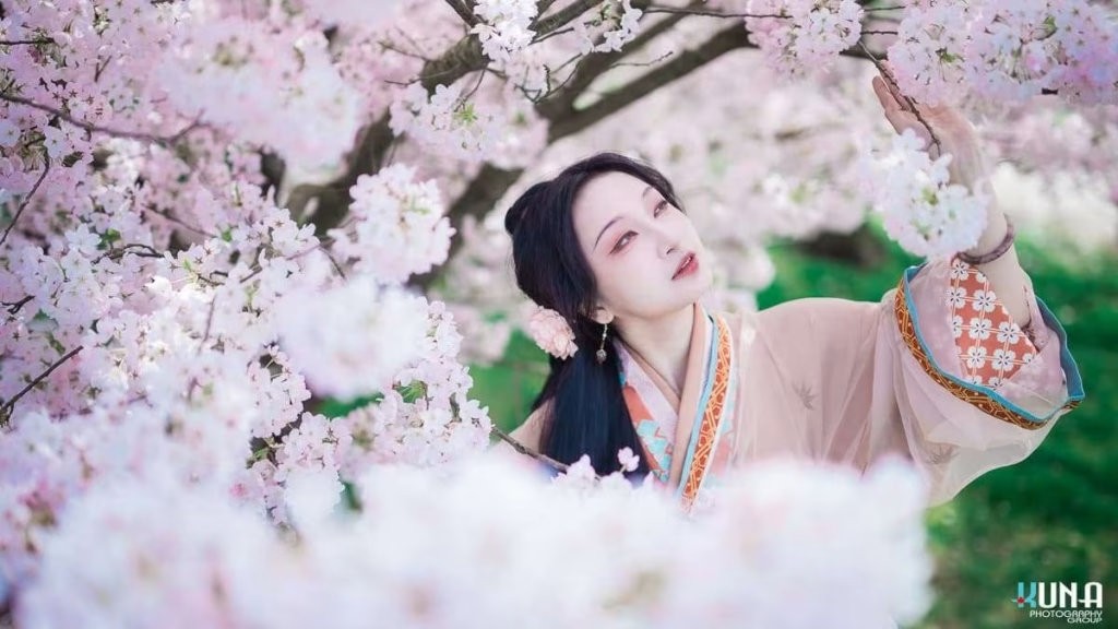 Low-angle hanfu photography in Richmond: Subject reaching for a high cherry blossom branch at Larry Berg Flight Path Park Metro Vancouver 2025.