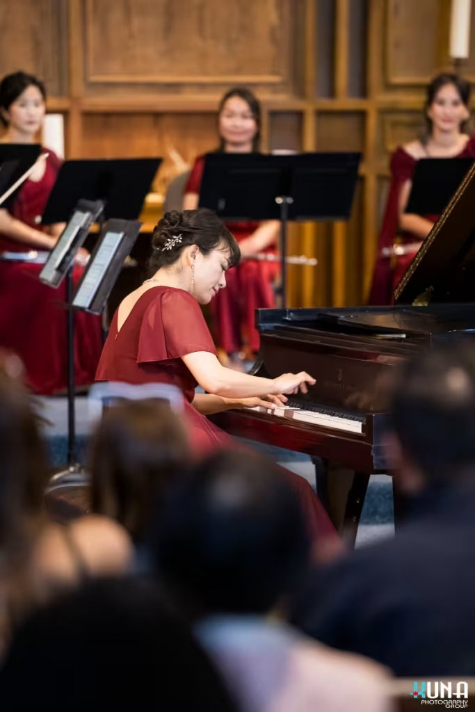 Profile view of a female pianist playing a grand piano during a classical performance