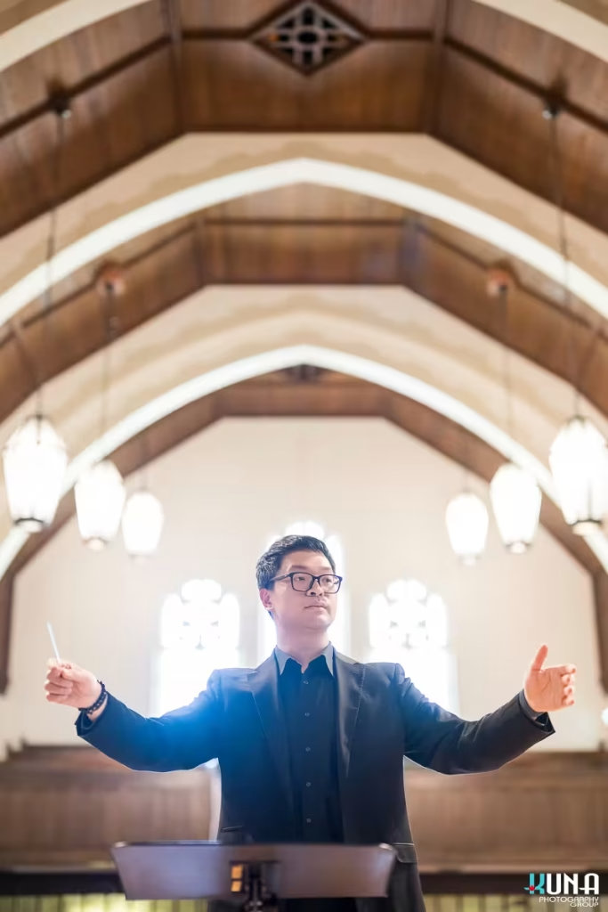 Orchestral conductor leading the Formosa Music Ensemble at a church venue in Metro Vancouver