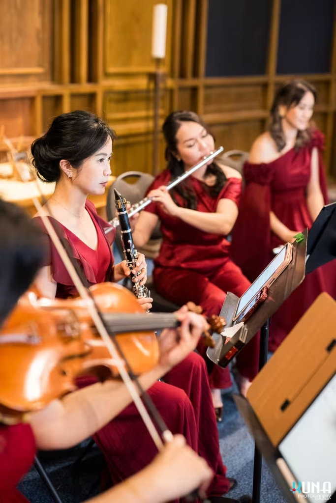 Wind and string musicians in elegant red dresses performing classical music at Pacific Spirit United Church