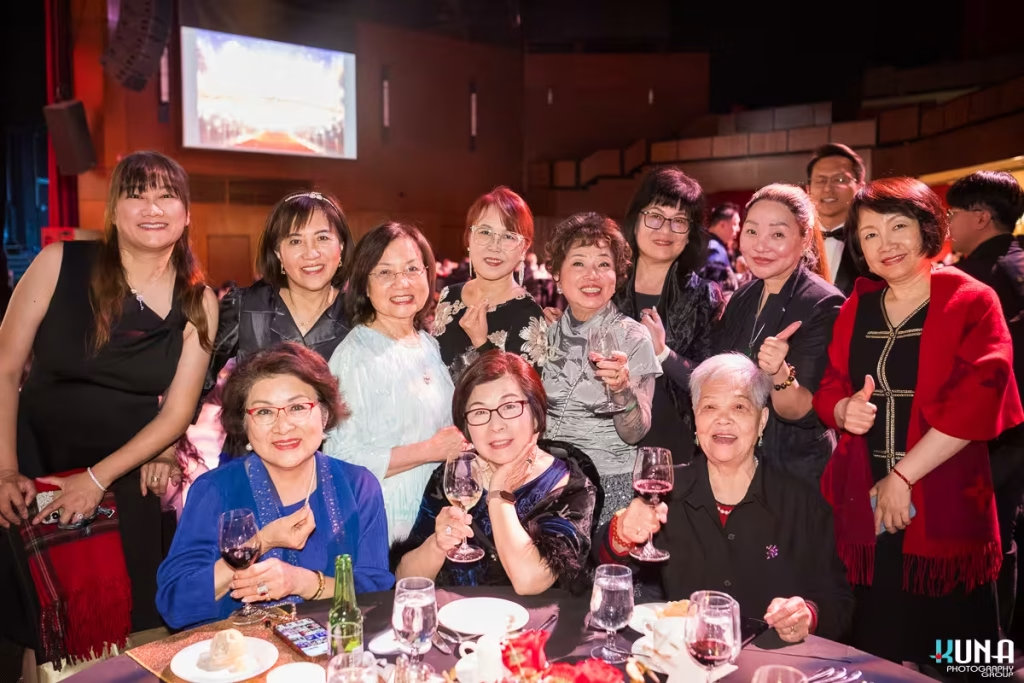 Elegant lady guests group portrait at River Rock Theatre banquet A smiling group of elegant female attendees raising white wine glasses at a gala table.