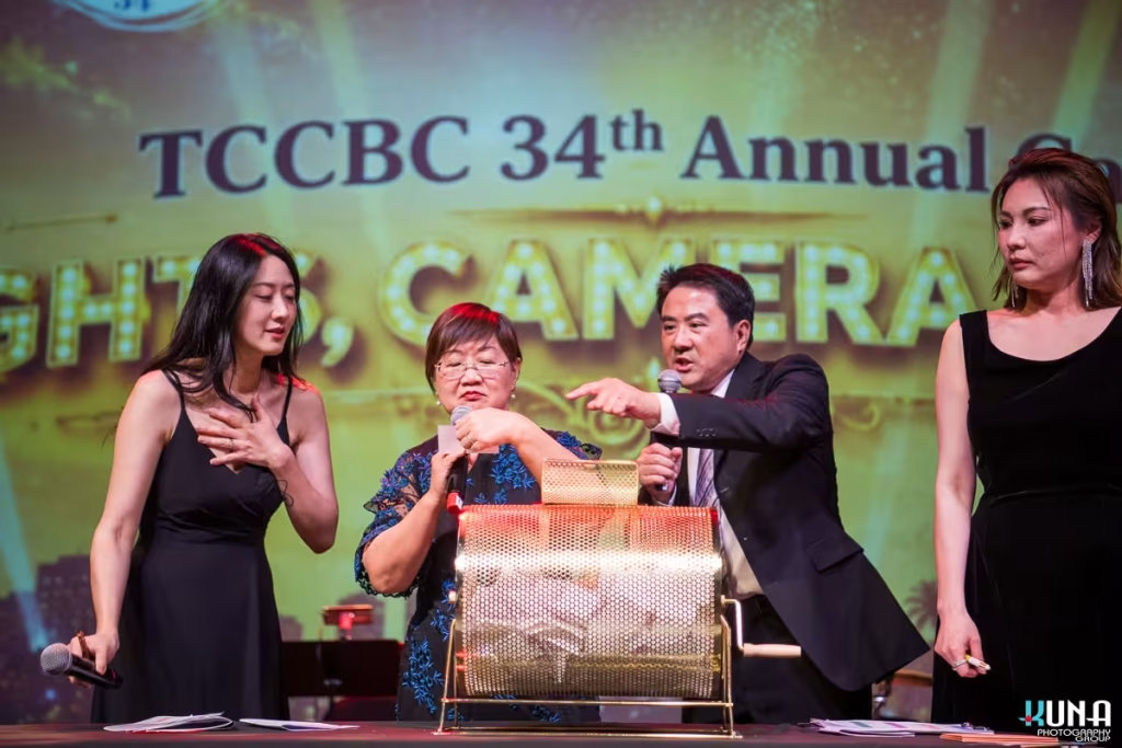 Golden raffle drum lucky draw stage photography Hosts spinning a golden lottery drum for the lucky raffle draw on stage.