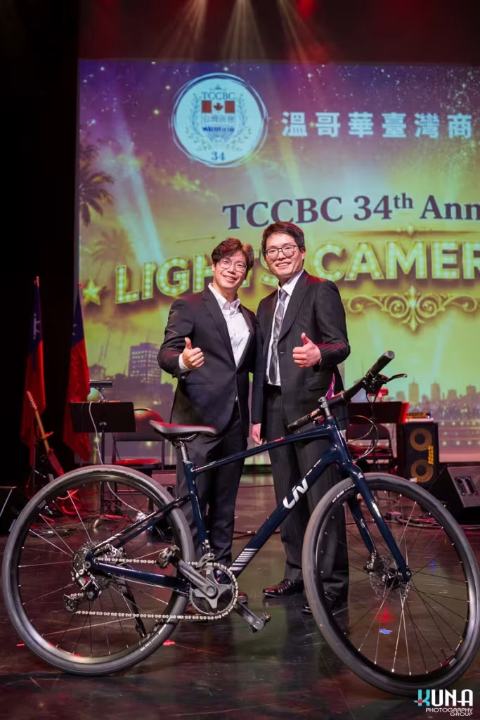 Grand prize bicycle raffle winner photography at TCCBC Gala Two gentlemen standing beside a premium dark blue Liv bicycle won at the raffle draw.