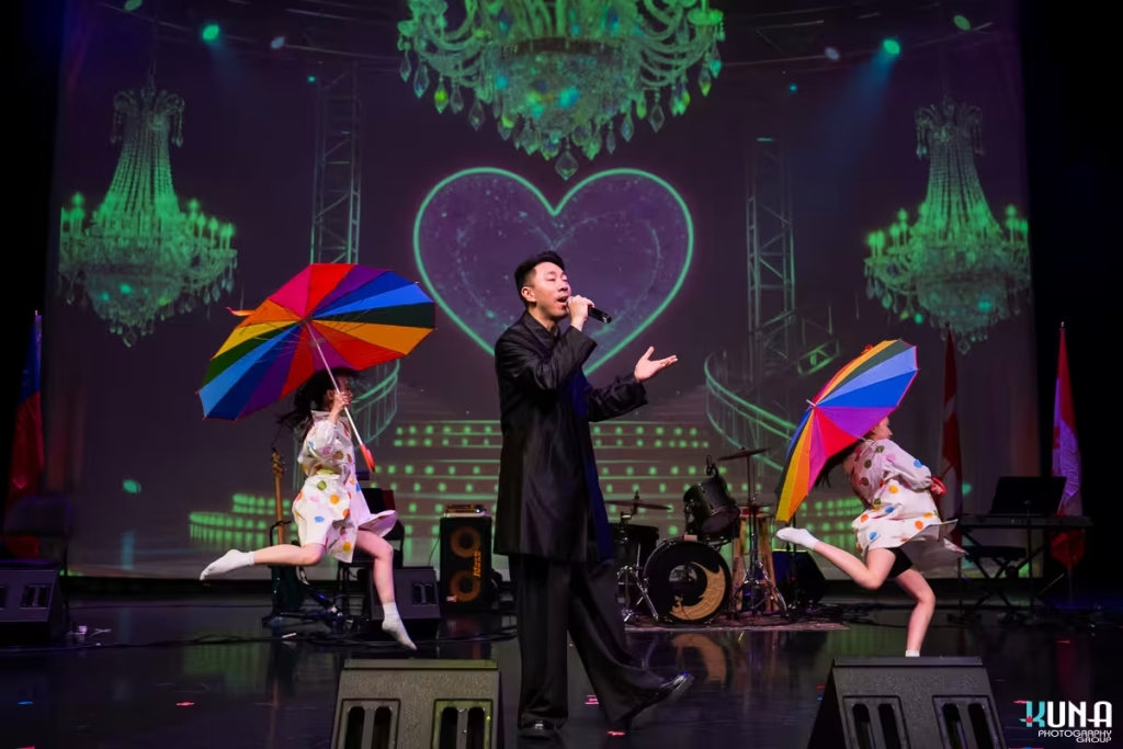 Spectacular live concert performance by Vancouver gala photographer A male singer performing live on stage accompanied by young dancers with rainbow umbrellas.
