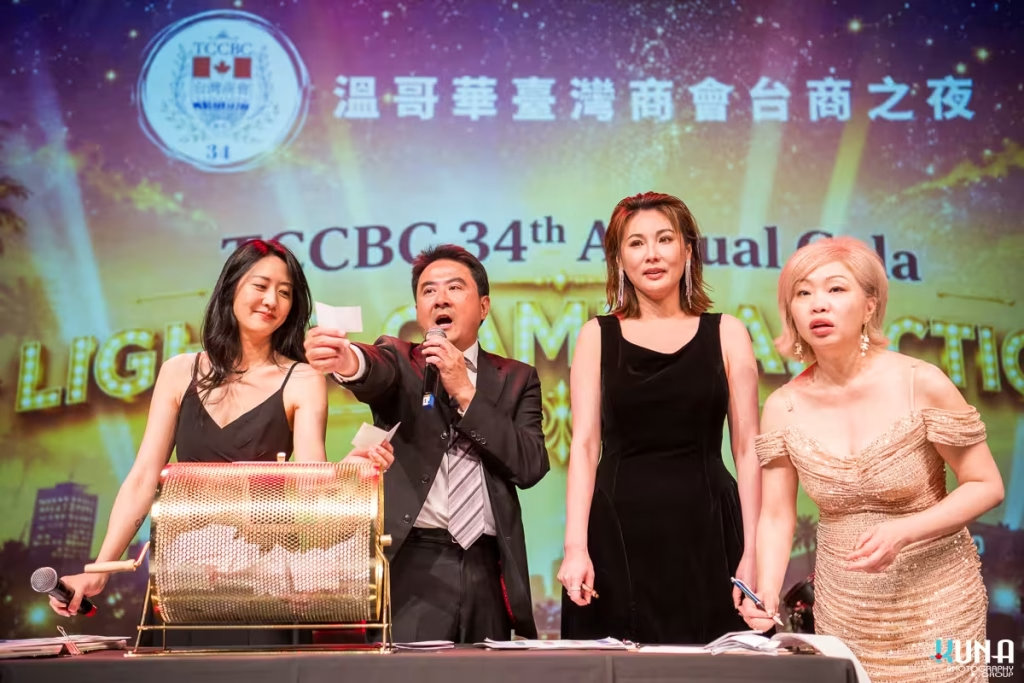 Dramatic raffle prize drawing moment on stage at Richmond gala On stage presenters expressing surprise while pulling a ticket from the gold raffle drum.