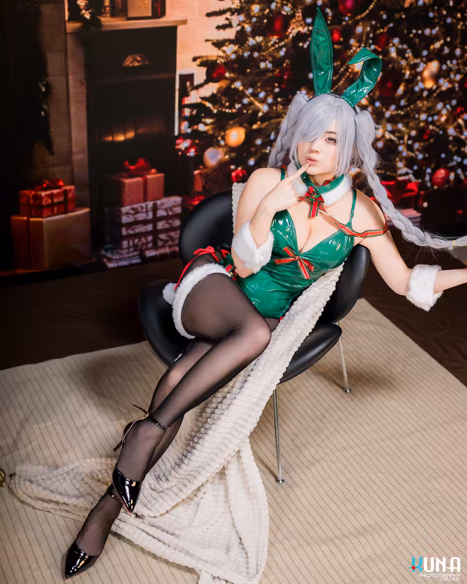 Cosplayer sitting elegantly in a modern chair against a glowing Christmas tree LED backdrop in Vancouver.