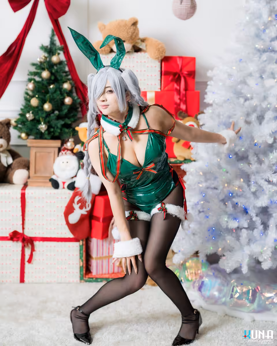 Cosplayer in a green holiday bunny suit striking a dynamic pose next to a glowing white Christmas tree in Vancouver.